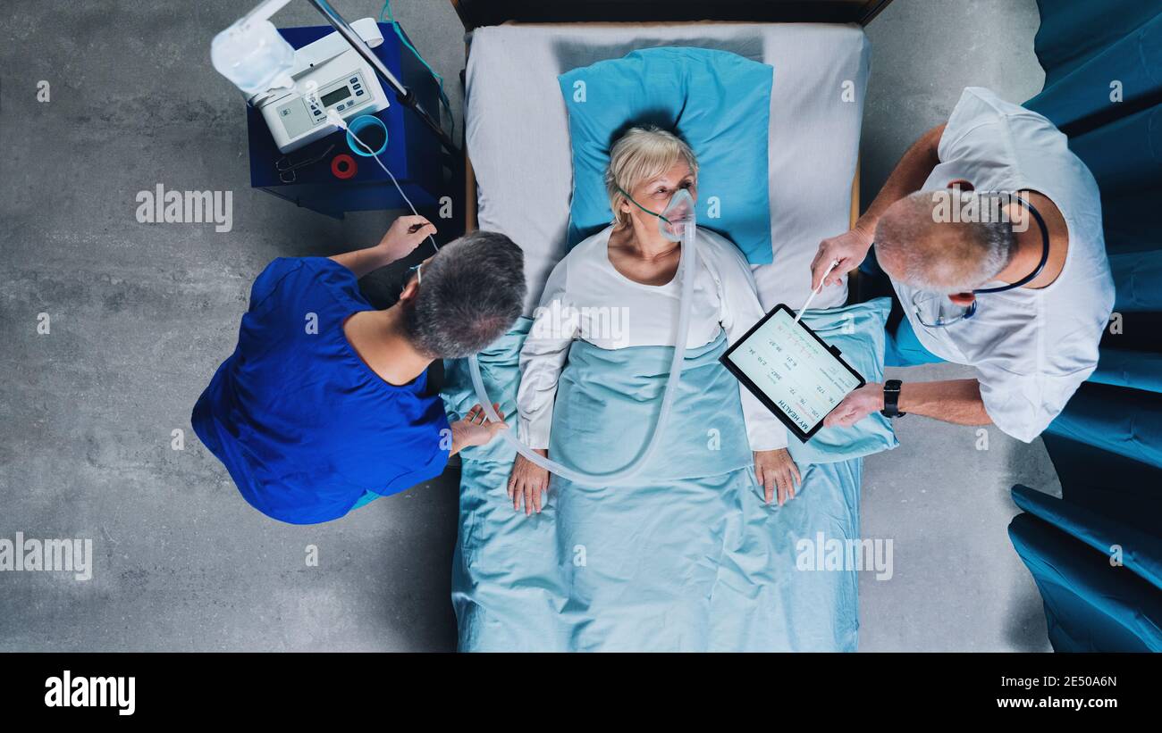 Vue de dessus des médecins et patient Covid-19 avec masque d'oxygène dans le lit à l'hôpital, concept de coronavirus. Banque D'Images