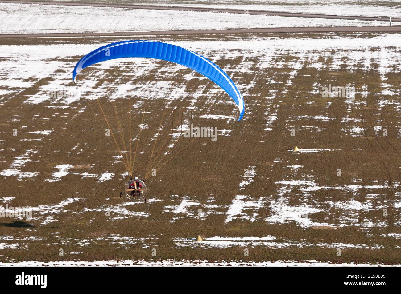Pilote de sports extrêmes volant avec un moteur à moteur paramoteur et un le parapente se prépare à atterrir sur la piste d'ulm Banque D'Images