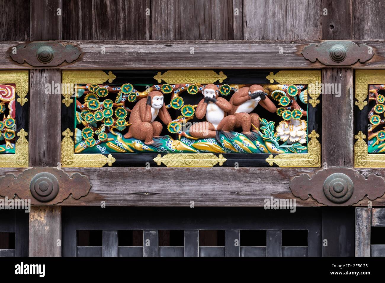Gros plan symétrique d'un bas-relief en porcelaine qui porte le trois singes sages encadrés par une structure en bois abîmé Banque D'Images