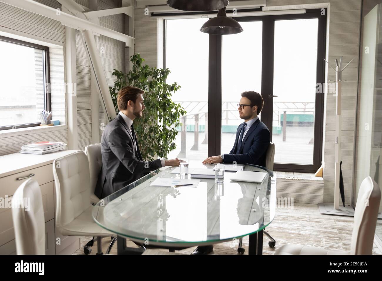 Deux hommes d'affaires confiants assis à table dans la salle de réunion, discutant du projet Banque D'Images