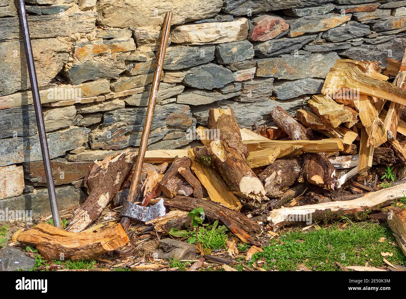 Une vieille hache en bois insérée dans un morceau de bois scié, vieux morceau de bois sur le fond de bois de chauffage haché. Banque D'Images