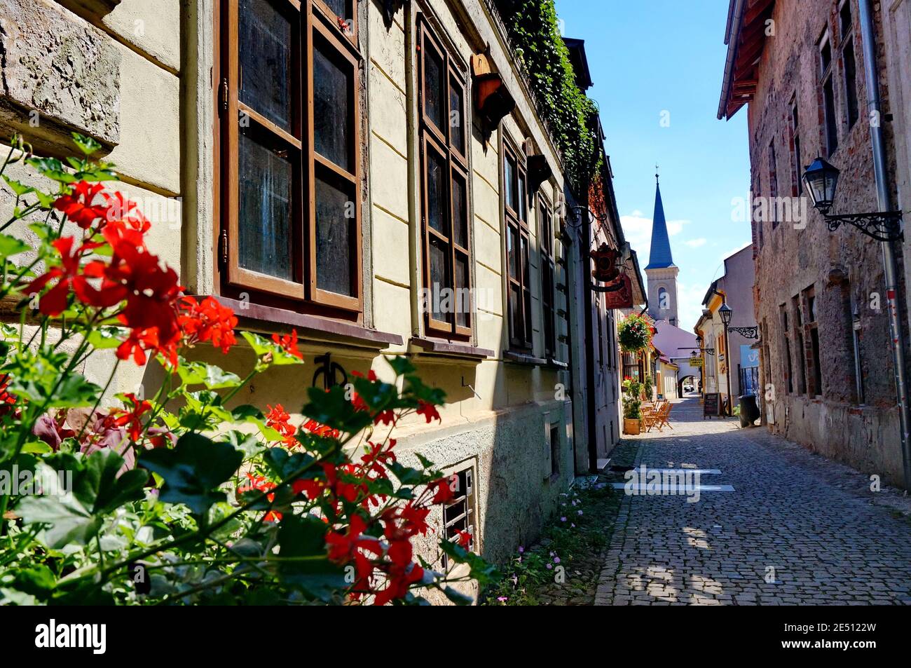 Belle rue vide étroite de la ville slovaque Kosice avec tour d'une église à la fin et fleurs rouges dedans le premier plan Banque D'Images