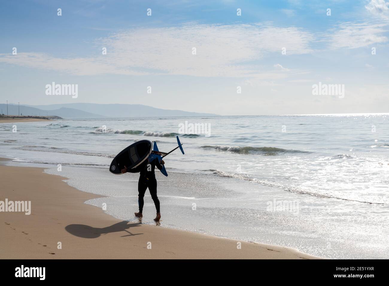 Barbate, Espagne - 19 janvier 2021 : surfeur marchant le long d'une plage avec une planche de surf hydrofoil Banque D'Images