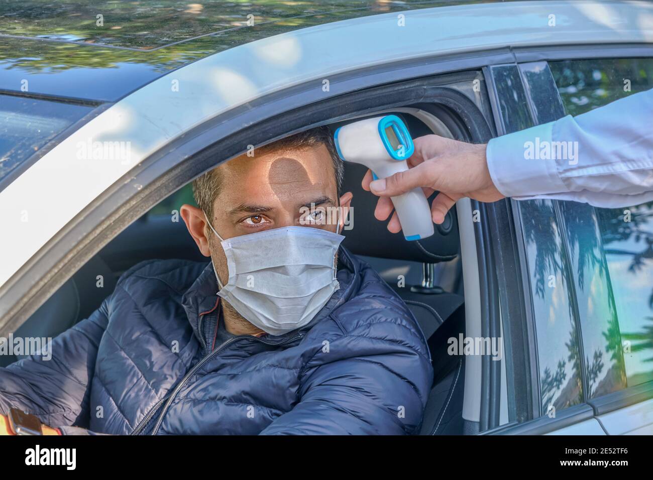 La sécurité mesure la température corporelle du conducteur à l'aide d'un thermomètre numérique infrarouge. Inspection de la température au cours d'une pandémie de coronavirus (Covid-19). Banque D'Images