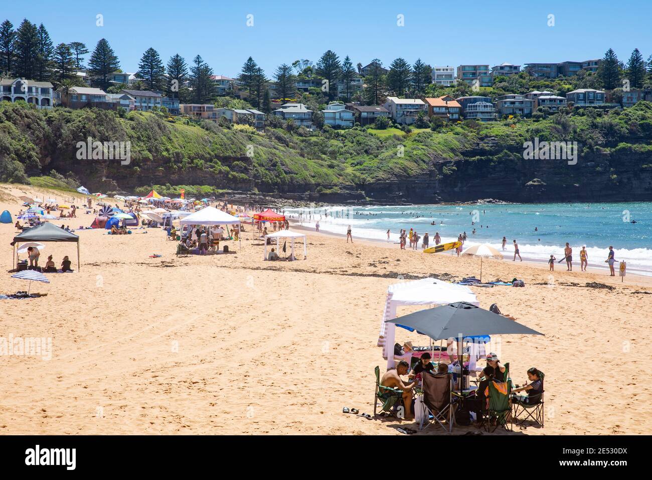 Bains de soleil sur Bilgola Beach Sydney pendant l'été australien chaud et Utiliser des cabanas et des parasols pour protéger le soleil et l'ombre, Sydney Banque D'Images