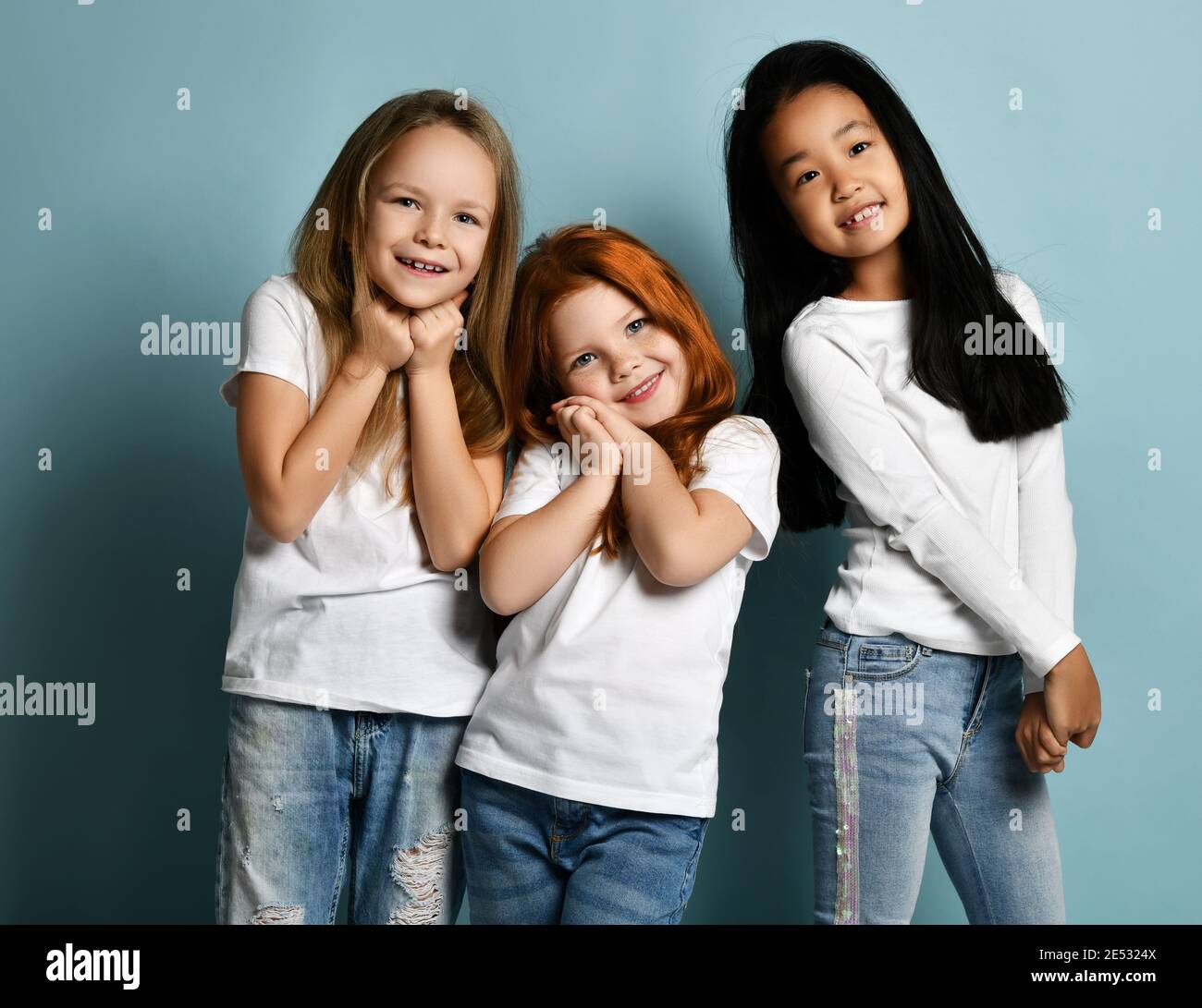 Mélange de race internationale enfants émotive filles en jeans et blanc les tee-shirts se tiennent ensemble pour fondre la sensation de toucher l'amour Banque D'Images