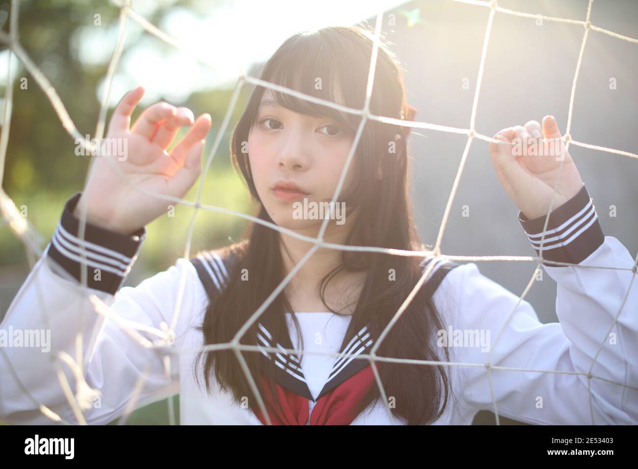 Portrait de l'uniforme asiatique de fille de lycée japonais regardant avec filets de buts de football Banque D'Images