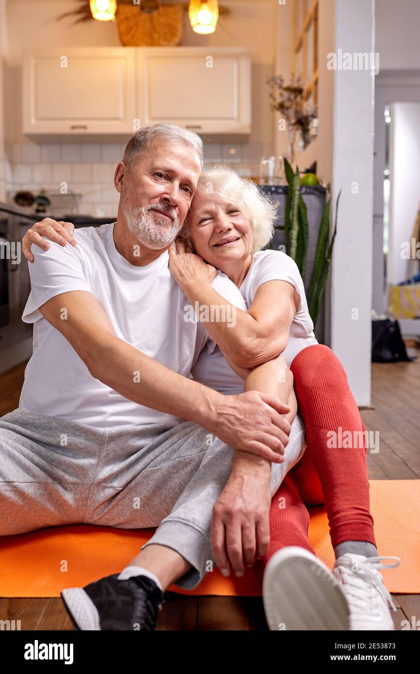 sportive homme et femme de 50-60 ans assis sur le sol prendre une pause après l'entraînement, les exercices de sport, regarder l'appareil photo sourire, heureux ensemble Banque D'Images