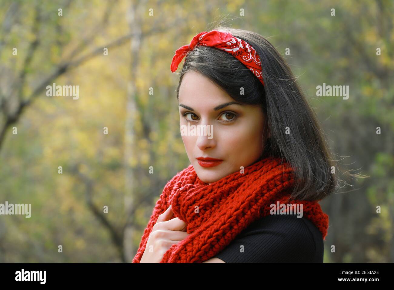 Belle jeune femme en manteau blanc, foulard rouge crochet et chapeau noir. Portrait plein air souriant en automne Banque D'Images