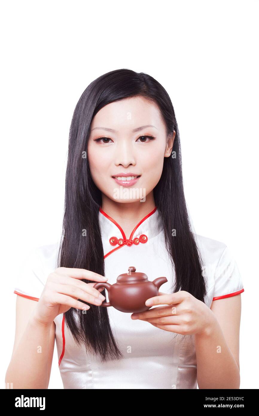 Portant cheongsam jeune femme orientale tenant une théière de haute qualité photo Banque D'Images