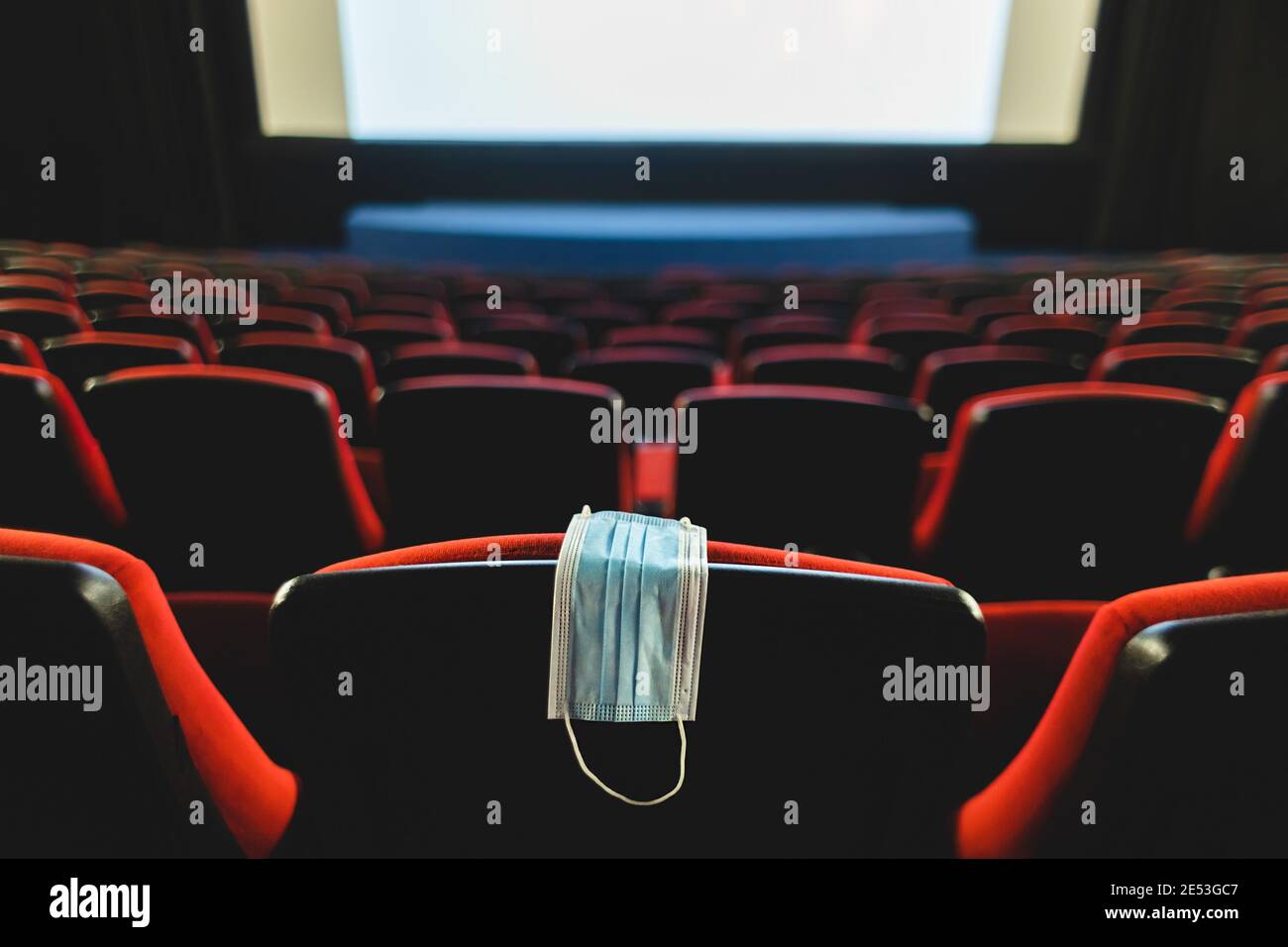 Un masque médical est suspendu sur une chaise dans une salle de cinéma vide. Pandémie et crise dans l'industrie. Premières de film retardées Banque D'Images