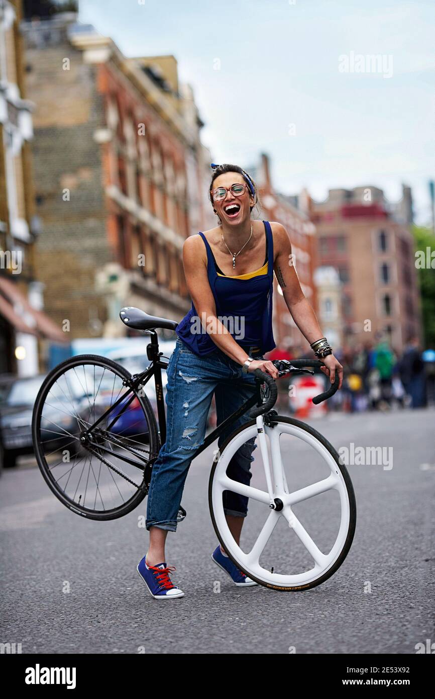 Femme joyeuse s'amusant avec un vélo dans la ville. Banque D'Images