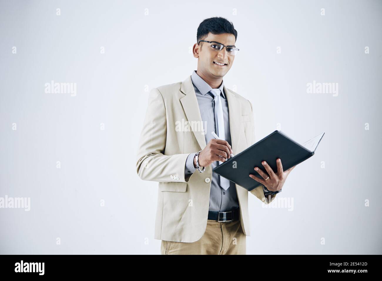 Studio portrait d'un jeune homme d'affaires indien charmant prenant des notes document Banque D'Images
