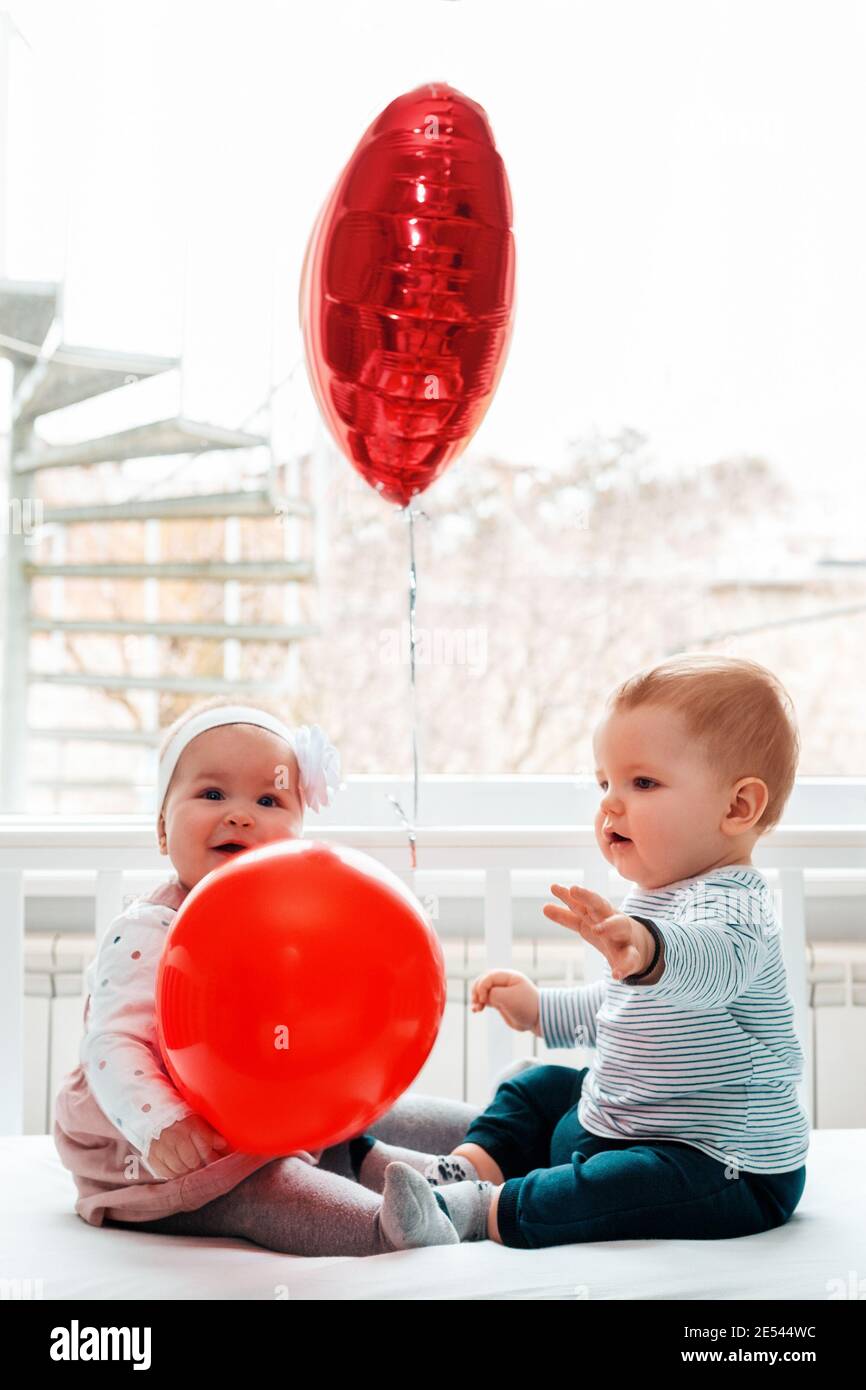 Saint Valentin. Bébé garçon et bébé fille assis dans un berceau avec des  boules rouges. Orientation verticale Photo Stock - Alamy