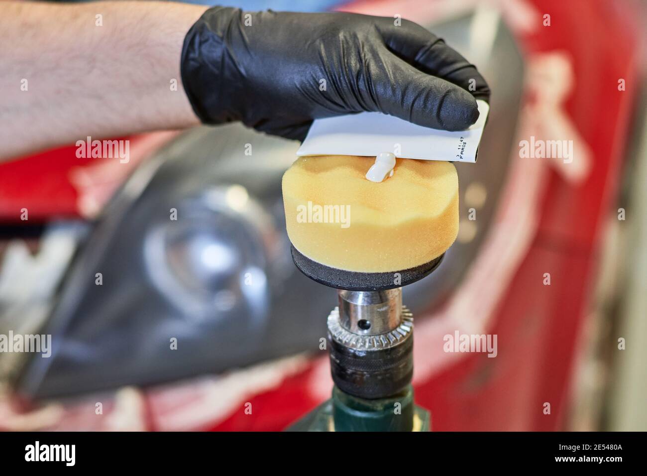 Mains humaines gantées plaçant une pâte sur une éponge de un outil de polissage pour polir les phares de voiture les outils de polissage et concept de travail Banque D'Images