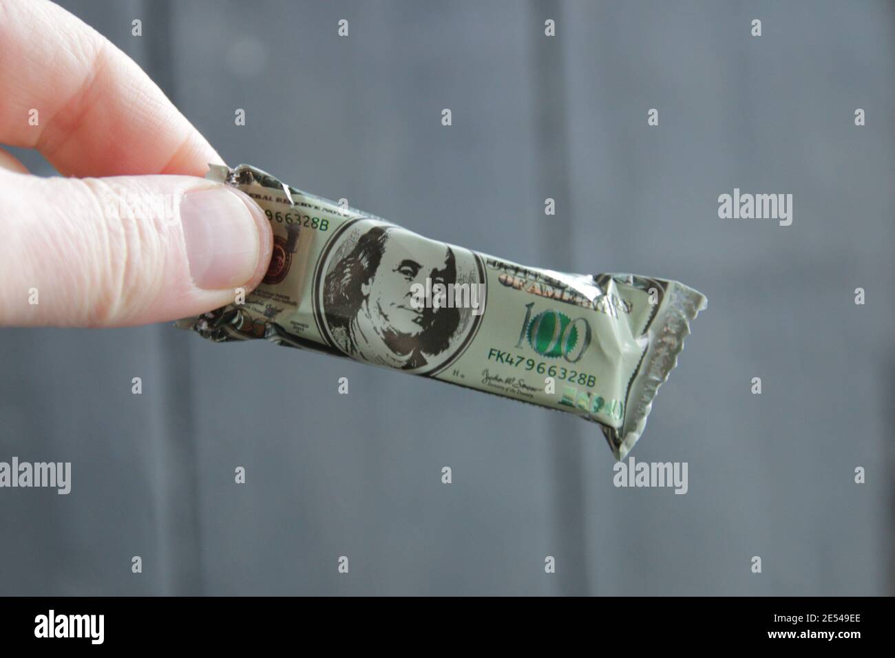 Bonus ou idée de prix. Une main tient une barre de chocolat sous la forme d'un billet de dollar. Banque D'Images