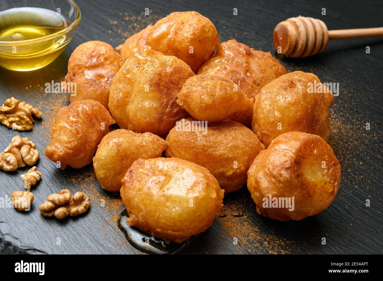 Petit pain maison servi avec du miel, des noix et de la cannelle sur un plat noir Banque D'Images