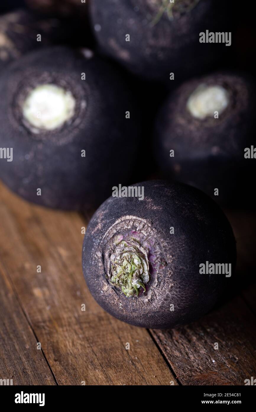 Radis noirs frais crus sur fond en bois. Banque D'Images
