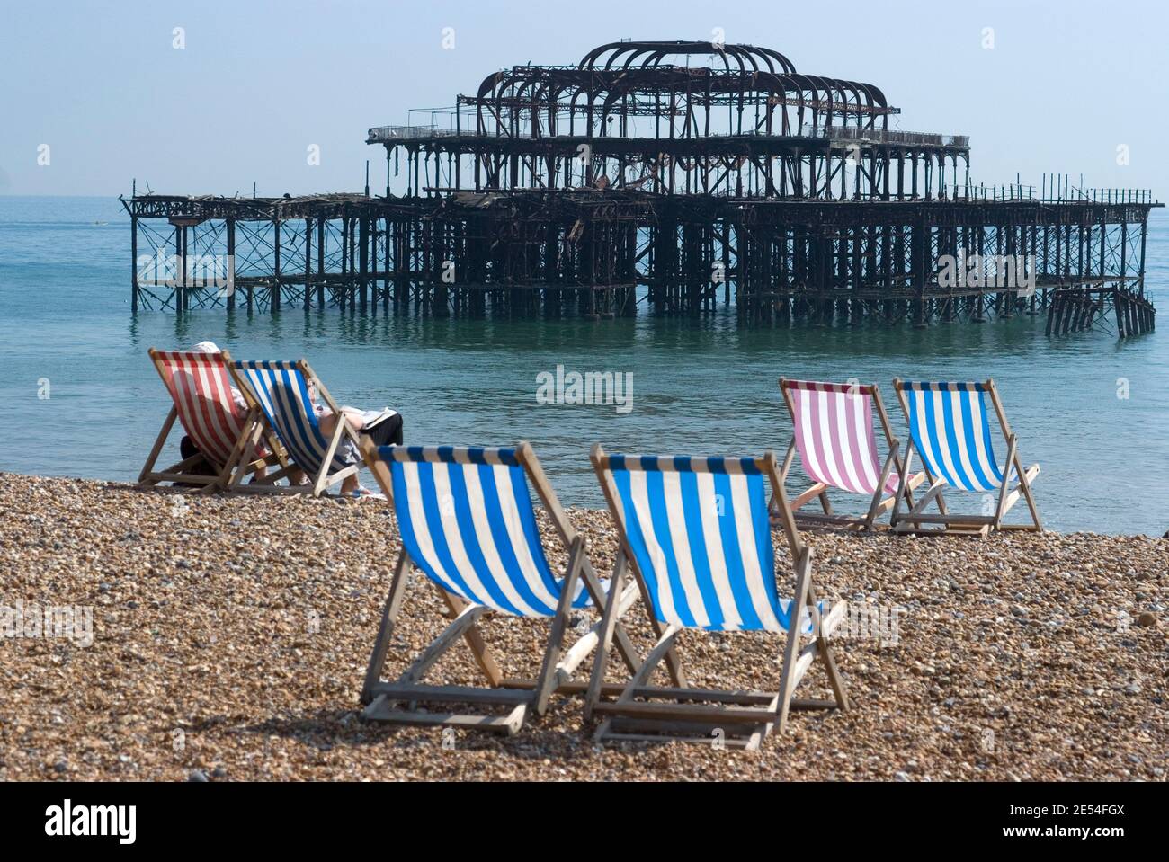 Transats sur le front de mer de la plage de galets avec les ruines de West Pier en arrière-plan, Brighton, Sussex, Angleterre | AUCUN | Banque D'Images