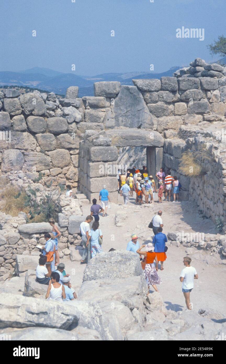 1986 Mycenae Grèce - site archéologique de Mycenae, porte du Lion de Mycenae et murs de la citadelle , Mycenae, Royaume du roi Agamemnon, dirigeant des Grecs dans la guerre de Troie. La vieille ville était entourée de gigantesques murs, tandis que l'endroit le plus célèbre est la porte du Lion, l'entrée de la ville avec deux lions de pierre femelles au-dessus. Ceci le côté inverse avec les touristes marchant jusqu'à la ville antique, site archéologique de Mycenae antique, Mycenae, Grèce, UE, Europe Banque D'Images
