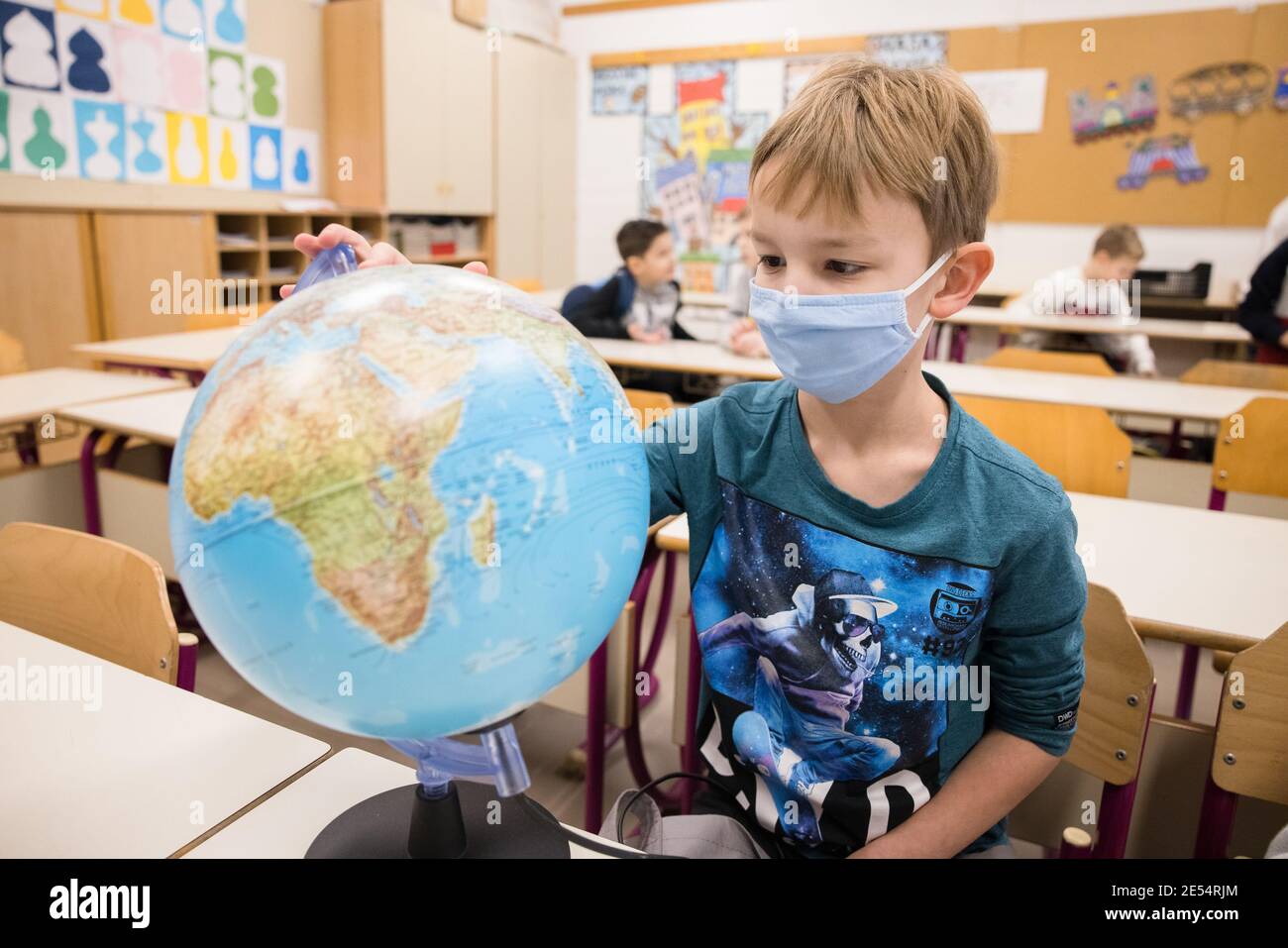 Kranj, Slovénie. 26 janvier 2021. Un garçon portant un masque facial examine un globe dans une classe alors que les élèves des trois premières années retournent à l'école primaire d'Orehek.après des mois de confinement, les écoles primaires en Slovénie ont rouvert pour les élèves des trois premières années. Crédit : SOPA Images Limited/Alamy Live News Banque D'Images