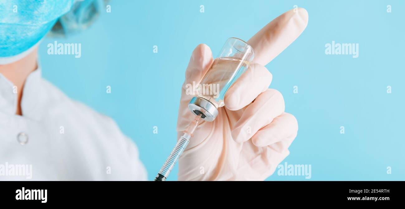 Médecin effectuant la vaccination dans un masque et des gants de protection. Covid 19 vaccin en flacon en verre flacon et seringue, médicament liquide dans la main du médecin Banque D'Images