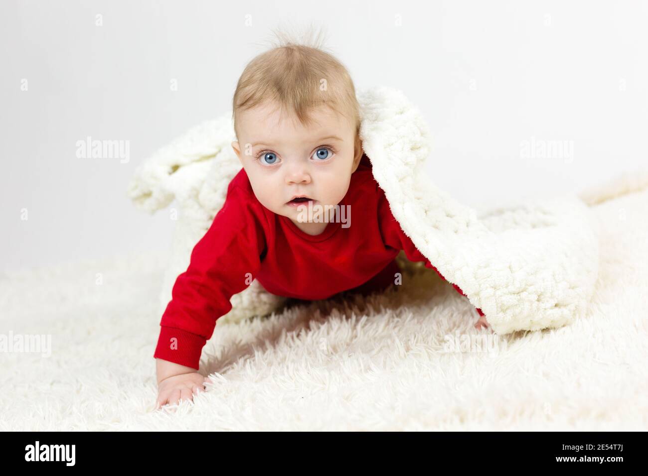 Un petit enfant recouvert d'une grande couverture blanche. Banque D'Images