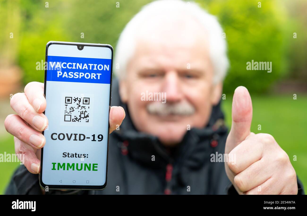 Homme âgé présentant un passeport de vaccination sur un téléphone portable, ce qui indique une vaccination contre le covid-19. Le téléphone affiche un code QR non fonctionnel. Banque D'Images