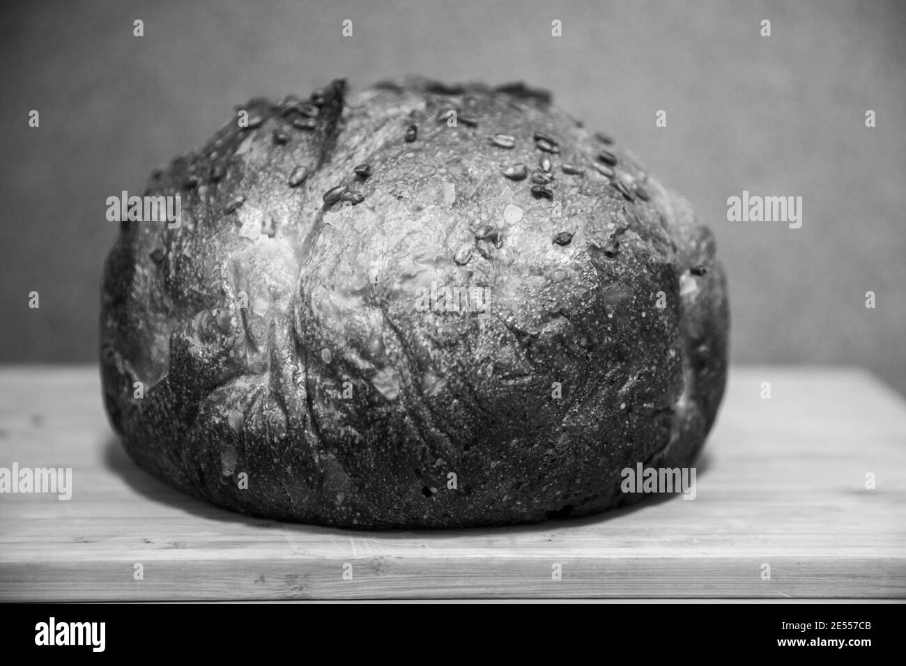 Pain fraîchement fait maison sur trancheuse en bois en noir et blanc Banque D'Images