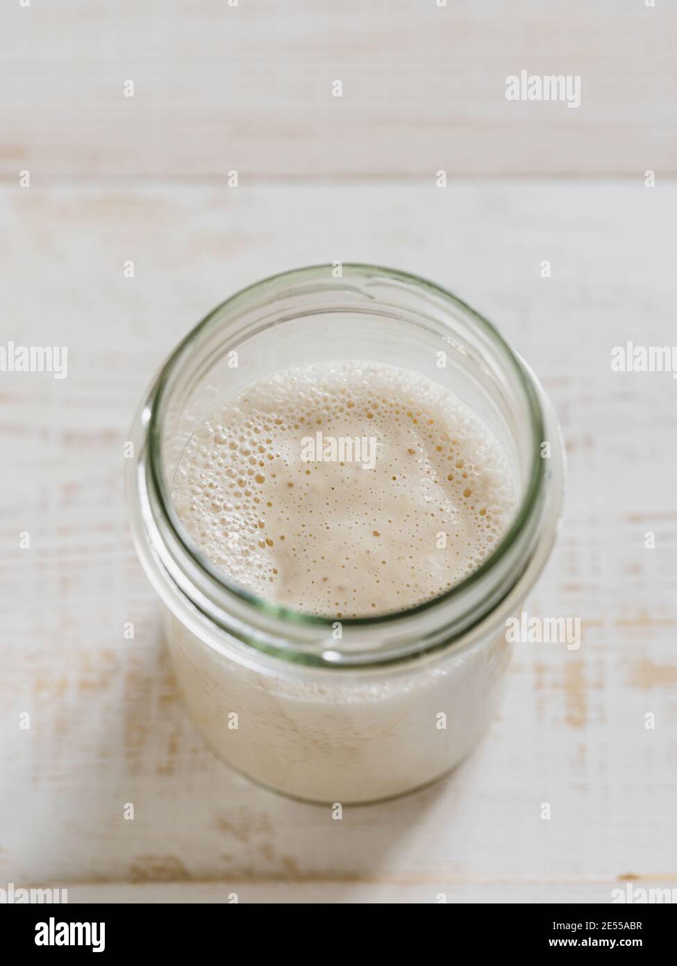 Démarreur de levain de blé. Vue de dessus du bol en verre avec démarreur de levain sur fond de bois blanc. Copier l'espace pour le texte ou la conception. Verticale. Banque D'Images