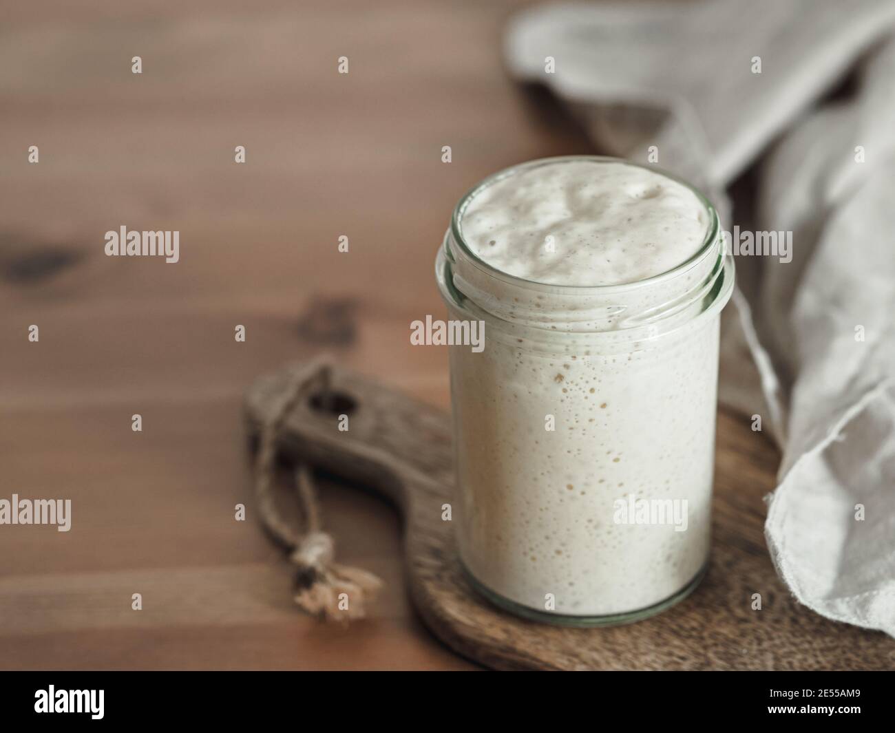 Démarreur de levain de blé. Bol en verre avec base de levain sur planche à découper en bois sur table en bois. Copier l'espace pour le texte ou la conception. Banque D'Images