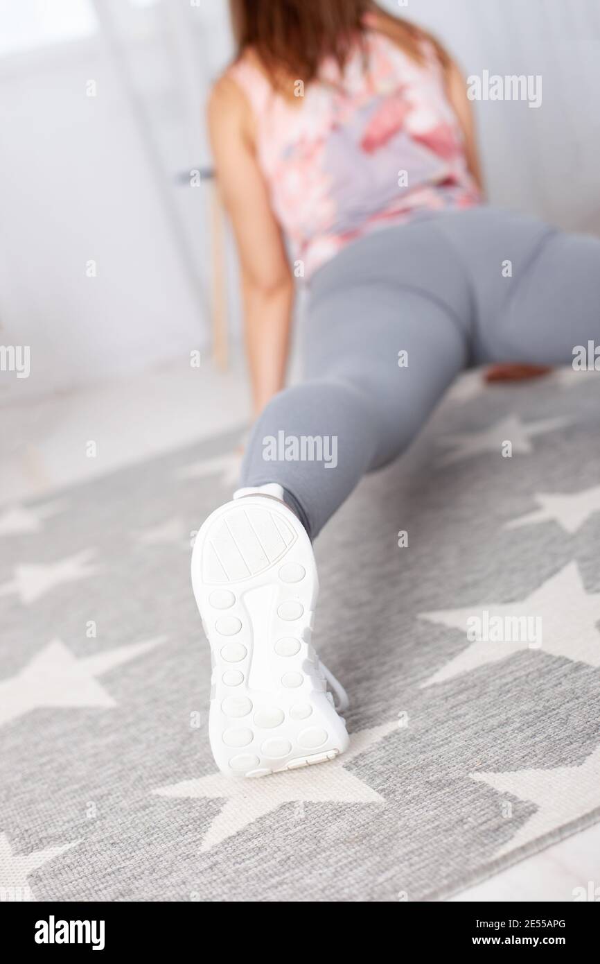 Vue arrière d'une femme en leggings gris à Surya Namaskara dans un intérieur de maison Banque D'Images