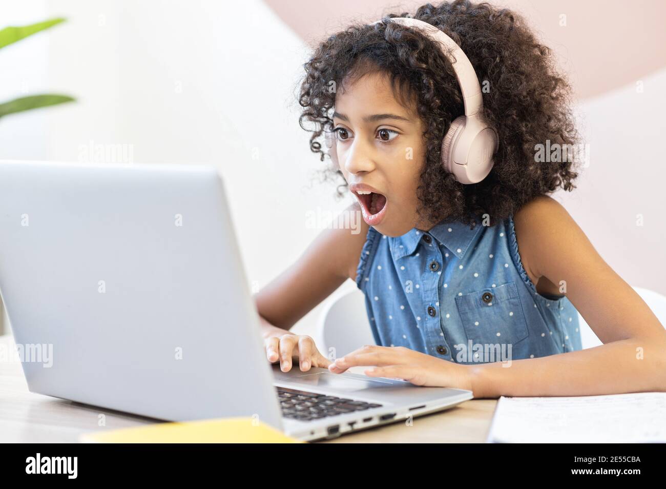 Une écolière africaine choquée regardant à l'écran d'un ordinateur portable avec la bouche ouverte, beaucoup de devoirs doivent faire sur l'apprentissage à distance Banque D'Images