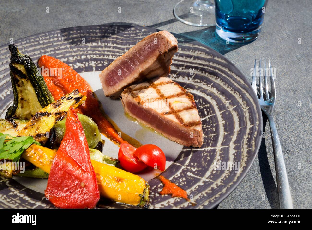 Gros plan et détail de la tranche de thon grillée avec grillé légumes et table en béton gris Banque D'Images