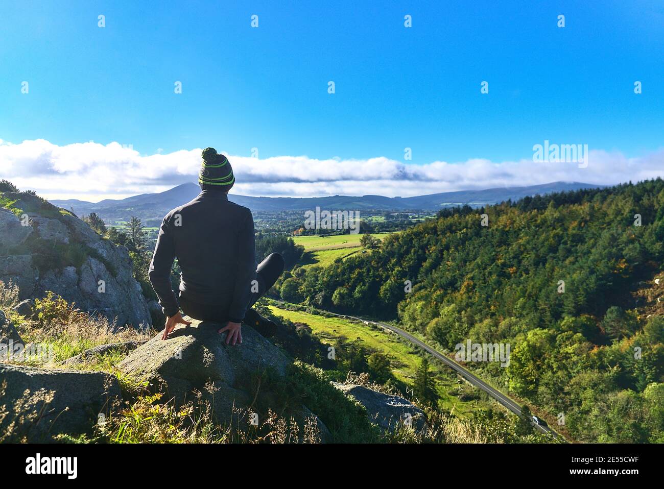 Jeune homme faisant de l'exercice de yoga et regardant les belles montagnes pittoresques dans les nuages lors d'une belle journée d'octobre, Co. Wicklow, Irlande. Déplacement Banque D'Images