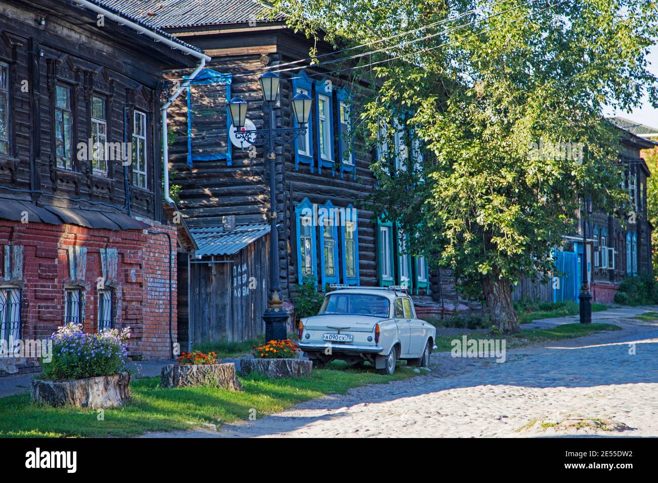 Rue pavée avec voiture soviétique classique Moskvich 408 et maisons traditionnelles en bois sibérien à l'oblast de Tomsk, Sibérie, Russie Banque D'Images