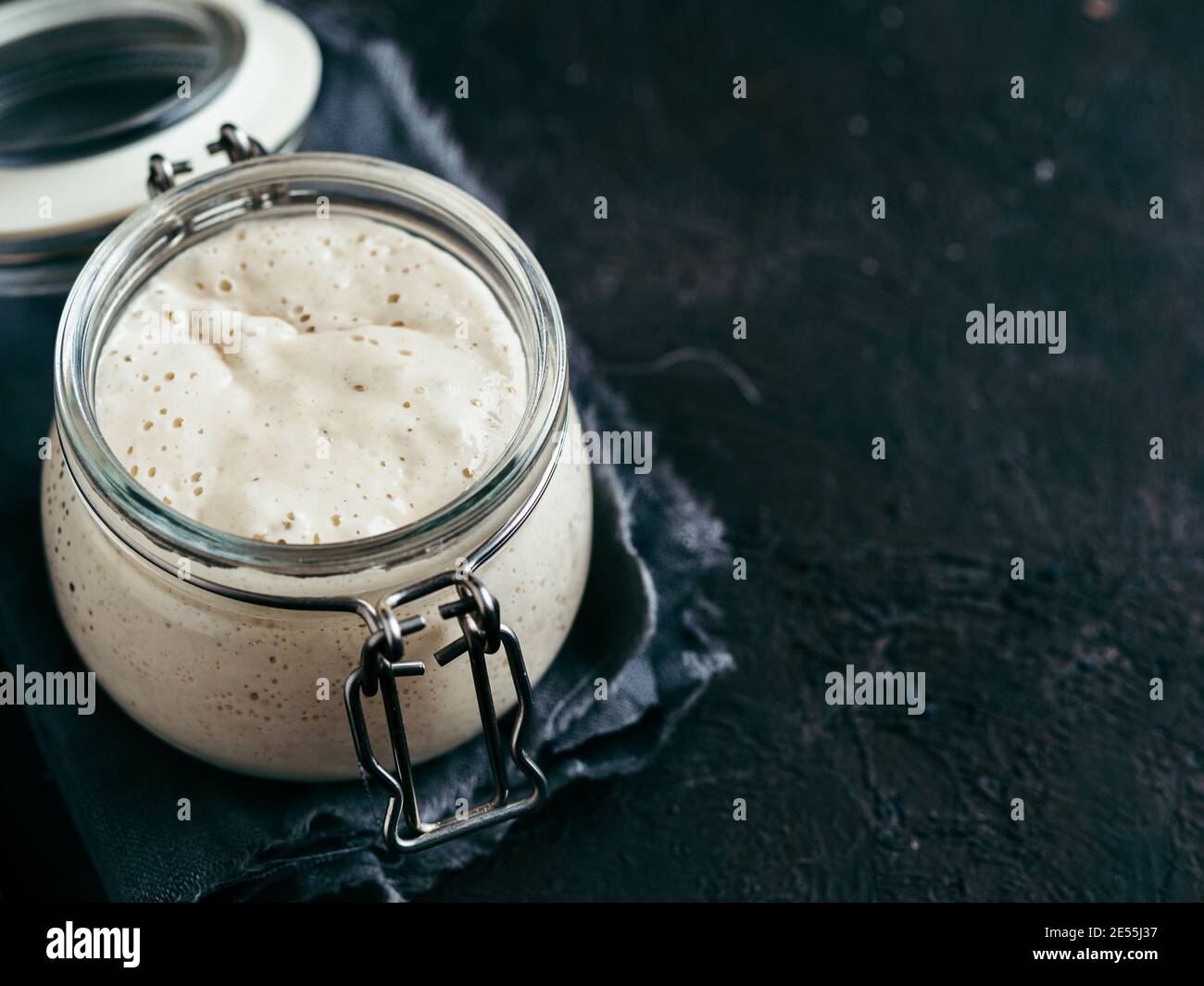 Démarreur de levain de blé. Bol en verre avec entrée de levain sur fond sombre avec espace de copie à droite Banque D'Images