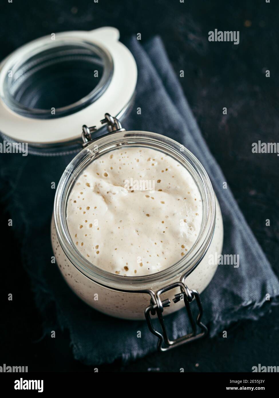 Démarreur de levain de blé. Bol en verre avec entrée de levain sur fond sombre, espace de copie. Verticale. Banque D'Images