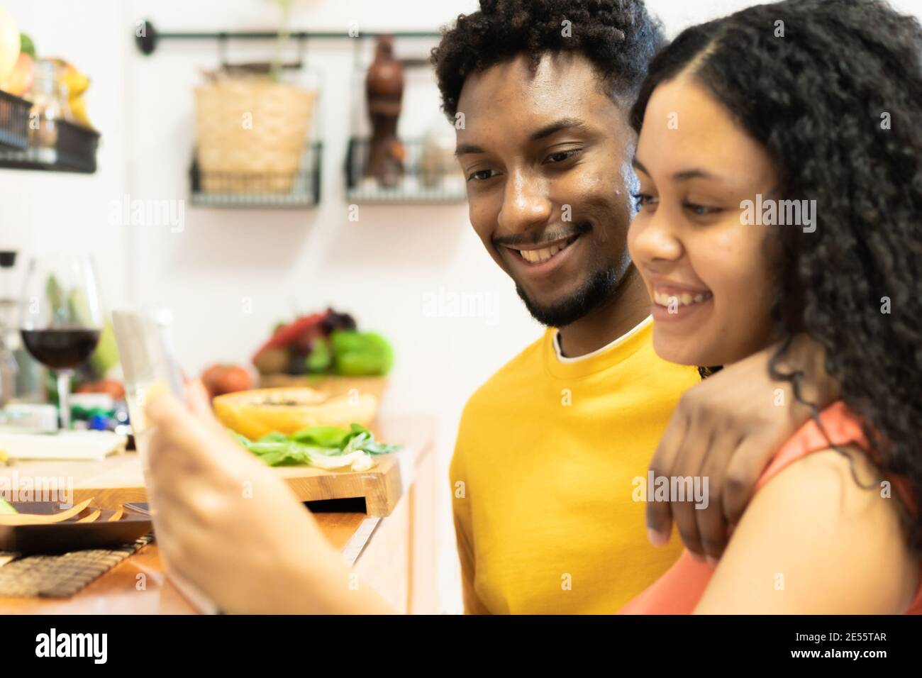Joyeux jeune couple regardant une tablette dans la cuisine pour une nouvelle recette. Beau jeune couple souriant tout en cuisant des aliments sains dans la cuisine à la maison. Amour, Banque D'Images