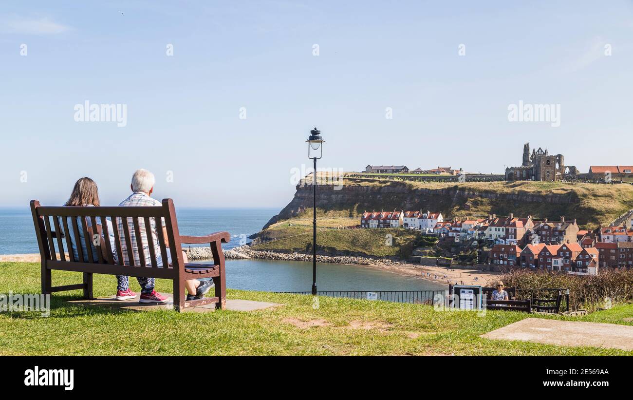 Couple sur un banc surplombant le port de Whitby. Banque D'Images