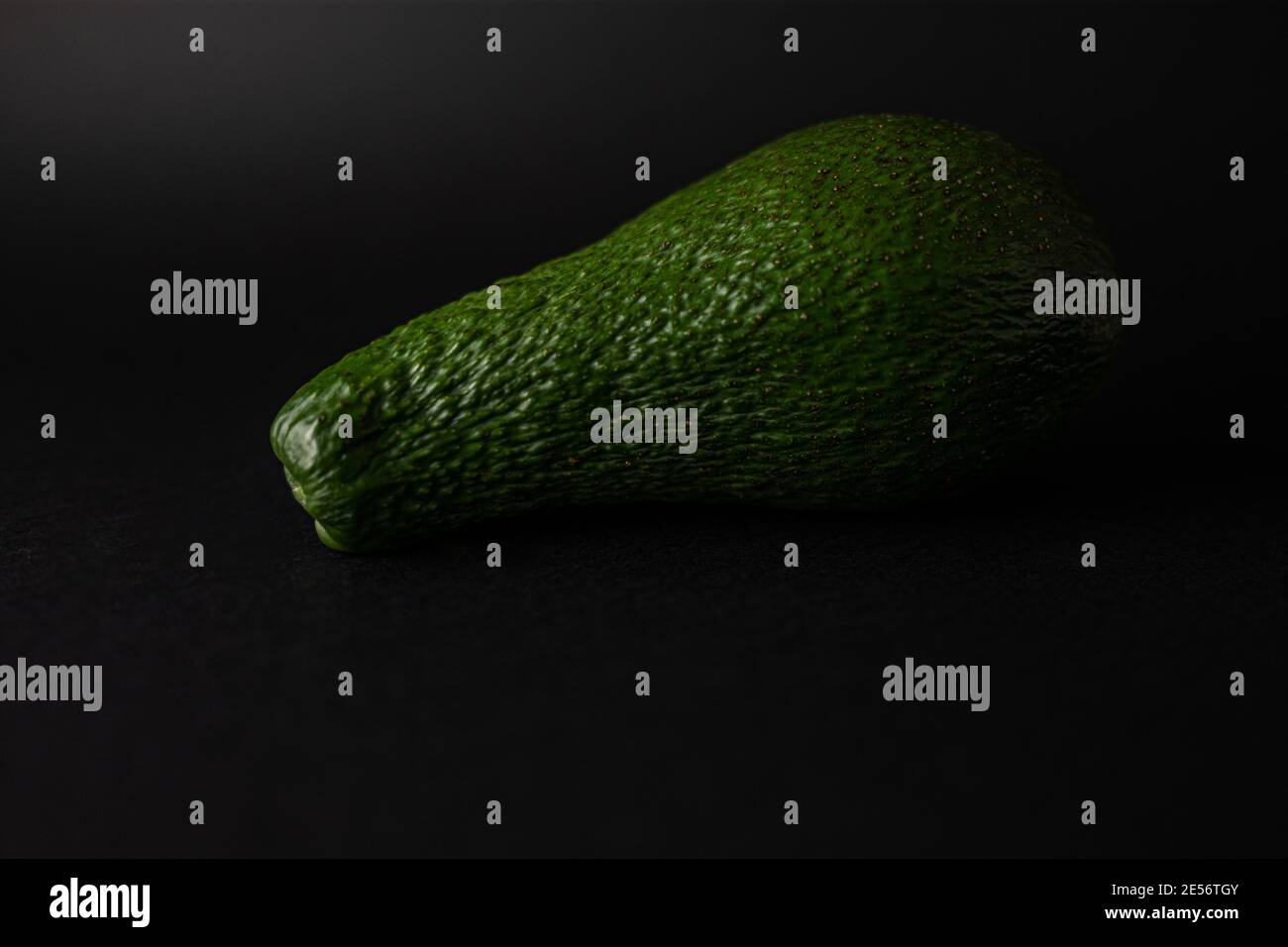Avocat vert mûr unique isolé sur fond noir Banque D'Images