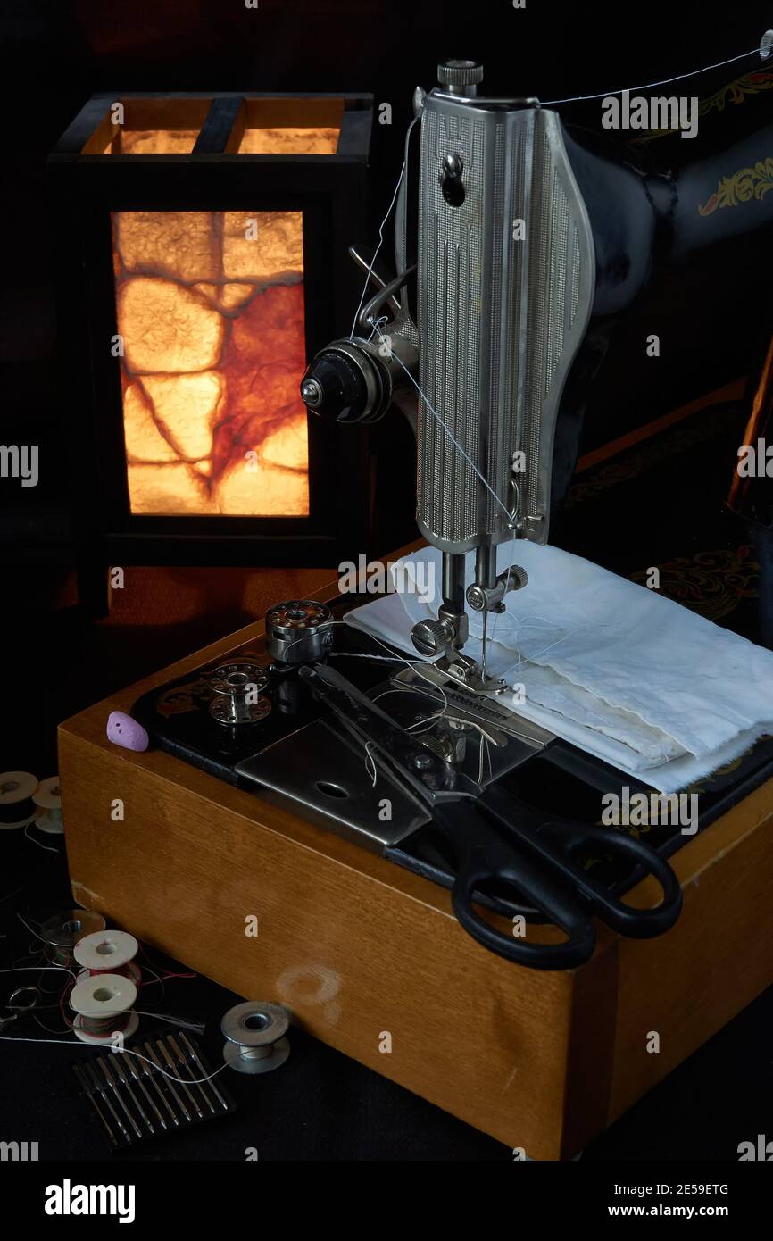 Machine à coudre et pièces sur fond sombre Banque D'Images