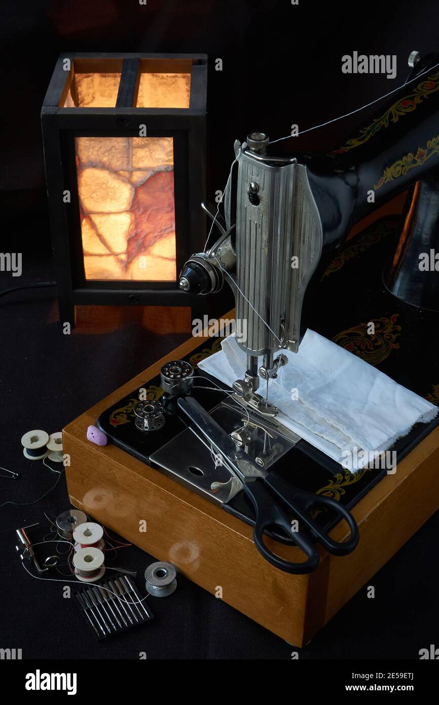 Machine à coudre et pièces sur fond sombre Banque D'Images