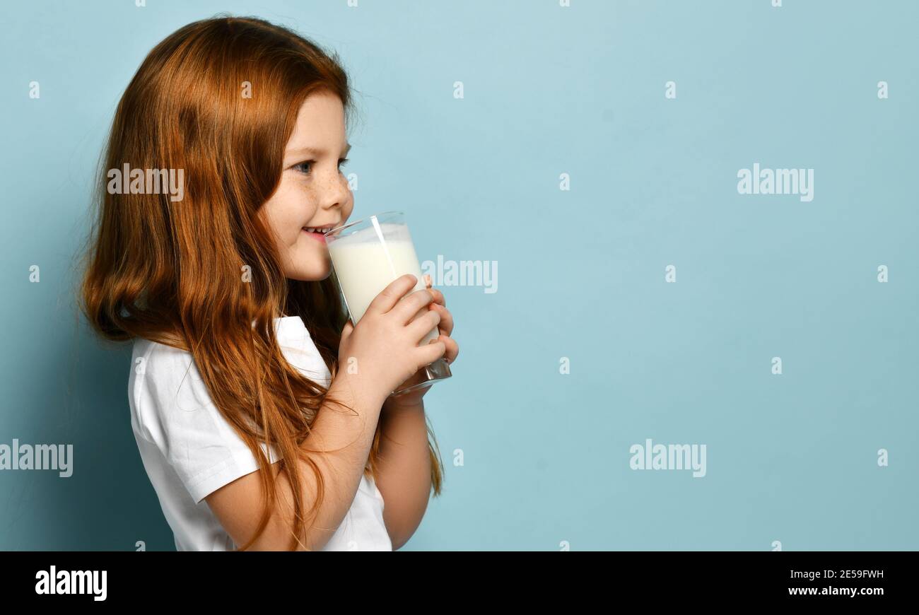 Joyeux rouge cheveux cheville fille se tient à côté de l'appareil photo tenir verre de lait ou de yaourt à boire en regardant la copie gratuite espace Banque D'Images