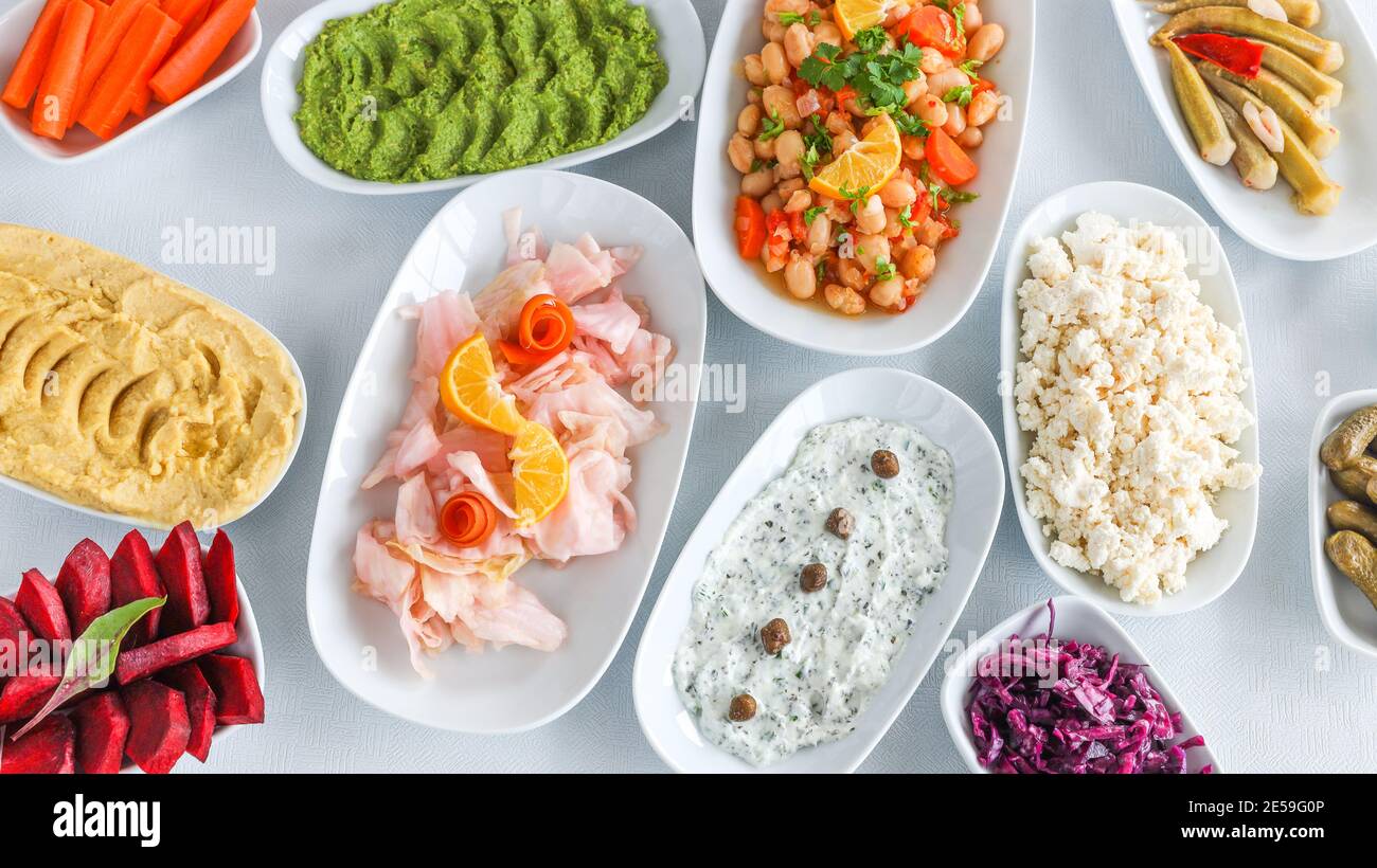 Vue de dessus de la table traditionnelle turque et grecque de légumes de dîner meze. Cuisine turque hors-d'œuvre froids (avec de l'huile d'olive) dans des assiettes blanches. Banque D'Images