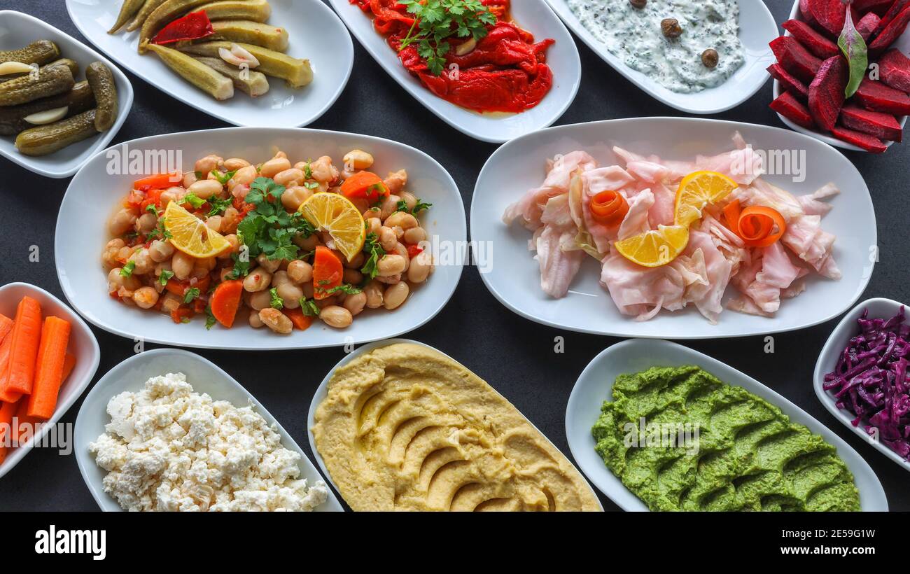Vue de dessus de la table traditionnelle turque et grecque de légumes de dîner meze. Cuisine turque hors-d'œuvre froids (avec de l'huile d'olive) dans des assiettes blanches. Banque D'Images