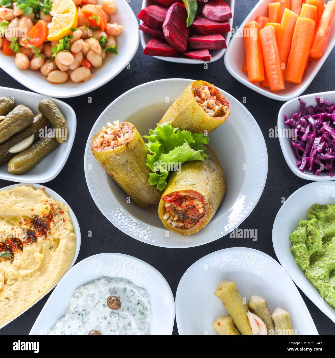 Table de meze traditionnelle turque et grecque avec courgettes farcies, houmous colorés, hors-d'œuvre froids (avec huile d'olive) dans des assiettes blanches. Banque D'Images