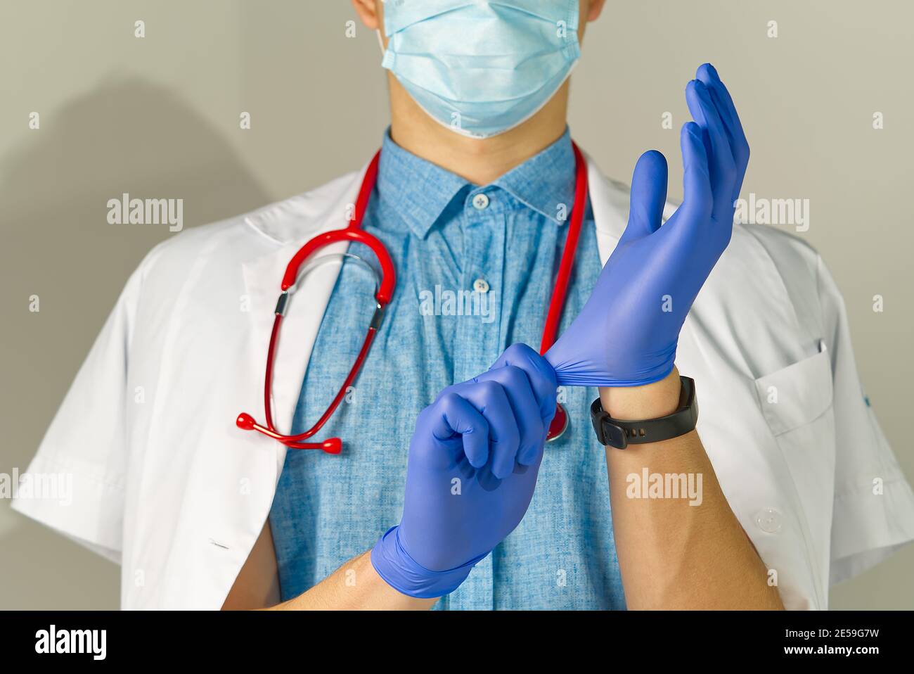 Gros plan lumineux du médecin avec stéthoscope rouge. Met sur des gants de protection, fond médical Banque D'Images