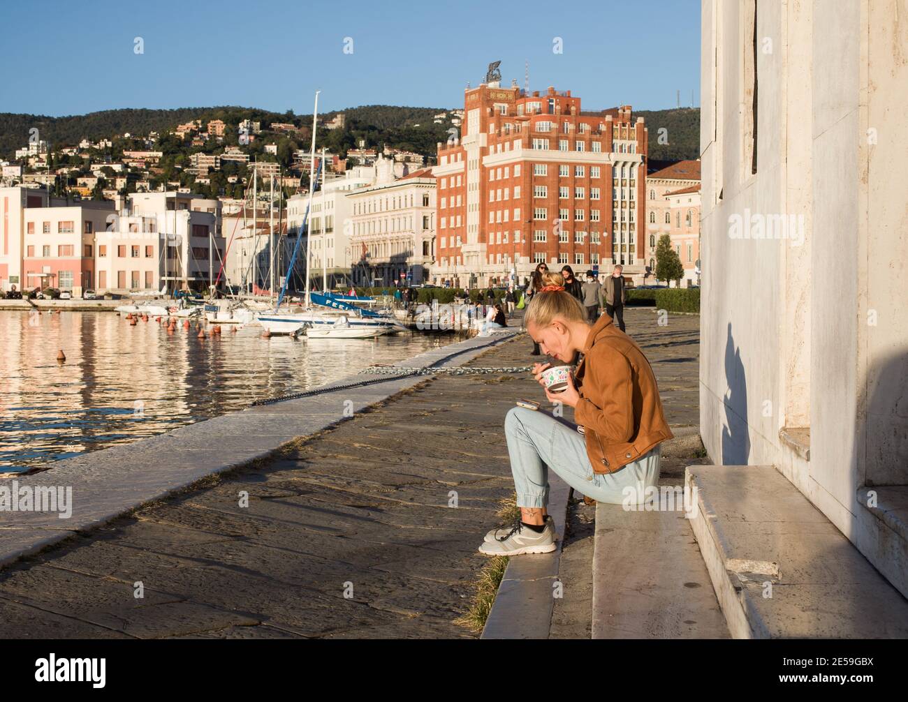 Trieste, Italie - octobre, 08: Jeune femme mangeant de glace sur la tasse assis sur la marche le 08 octobre, 2020 Banque D'Images