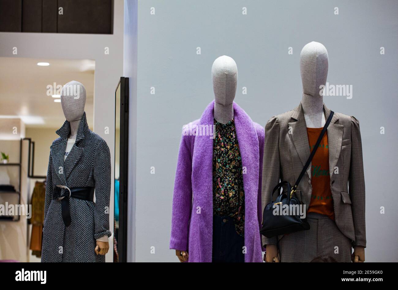 Vue des mannequins portant des manteaux dans la fenêtre d'un magasin de vêtements Banque D'Images